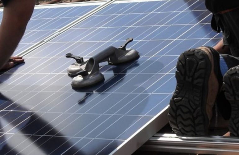 workers aligning solar panels on a roof